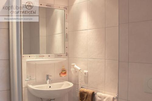 Un baño blanco con lavabo y espejo. en Alpenperle, en Ischgl