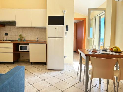 een keuken met een witte koelkast en een tafel bij Holihome Vascello A7 in Tortoreto Lido