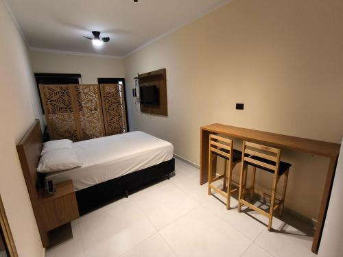 Centro comercial João Batista Julião في غوارويا: غرفة صغيرة بها سرير وطاولة ومكتب
