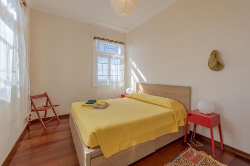 a bedroom with a yellow bed and a red table at Flora Garden House by HR Madeira in Estreito da Calheta