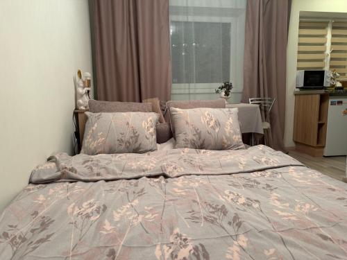 Tiny Paradise self check-in في نارفا: سرير كبير مع لحاف وردي ووسائد