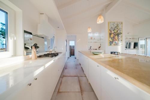 una cucina con armadi bianchi e un bancone lungo di Villa Verso Comporta - NEW! a Monte da Carrasqueira