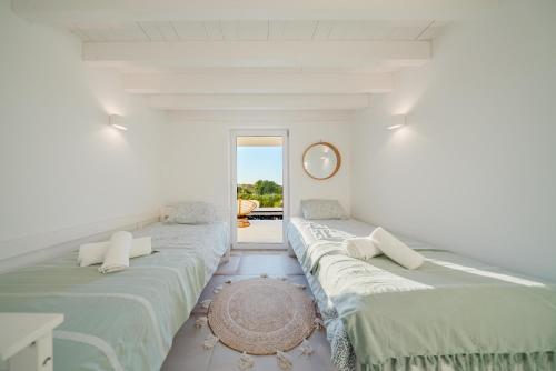 una stanza bianca con due letti e uno specchio di Villa Verso Comporta - NEW! a Monte da Carrasqueira