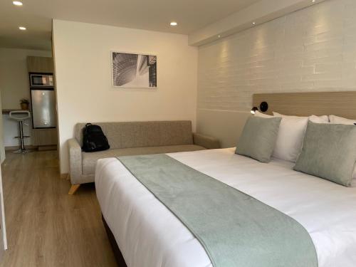 a hotel room with a large bed and a couch at Nova Iorque Suites by Avia Suites in Bogotá