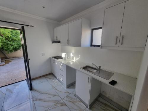 una cucina con mobili bianchi e un lavandino di Bird Whistle a Zeekoevlei