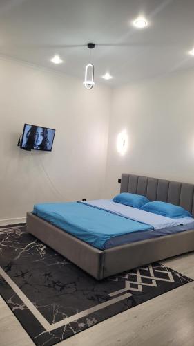 a bed in a room with a tv on the wall at Однокомнатная квартира посуточно in Astana