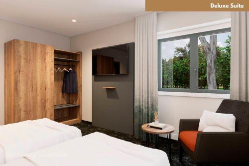 a bedroom with a bed and a chair and a window at Hotel Zur Post in Ismaning