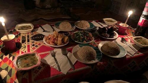 una mesa con platos de comida en una mesa con velas en Tours of the White Desert, en Az Zabū