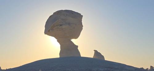Una estatua de roca frente al atardecer. en Tours of the White Desert, en Az Zabū