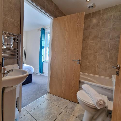 a bathroom with a toilet and a sink and a tub at Coventry Retreat - Modern 2 Bed Apartment in Spon End