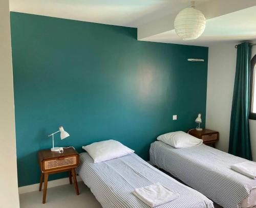 een kamer met twee bedden en een blauwe muur bij Beautiful house Ciboure pool designed in Ciboure