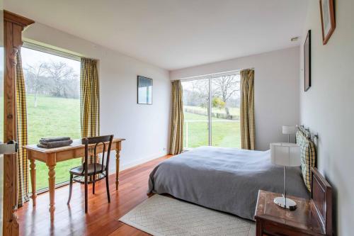 a bedroom with a bed and a desk and a window at Maison Percheronne by Green Folies, 15p & piscine in La Gaudaine