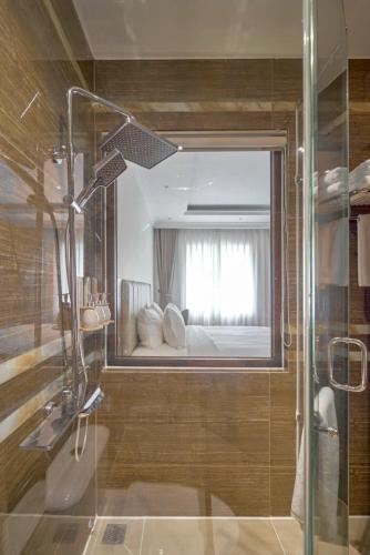 a bathroom with a glass shower and a bed at Lyns Hotel in Nhơn Trạch