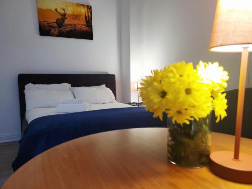 a vase of yellow flowers on a table with a bed at Cosy in Cork in Cork