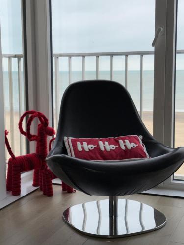 a black chair with a red pillow in a room at Malouki Koksijde - 4 star appartment with magnificent sea view in Koksijde