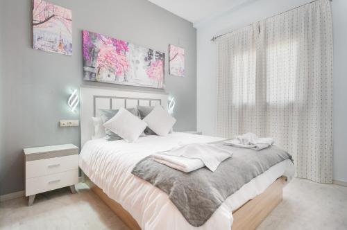 a bedroom with a bed with white sheets and a window at Apartamento Deluxe 1 Room Piscina Parking LuxSevilla Bormujos in Bormujos
