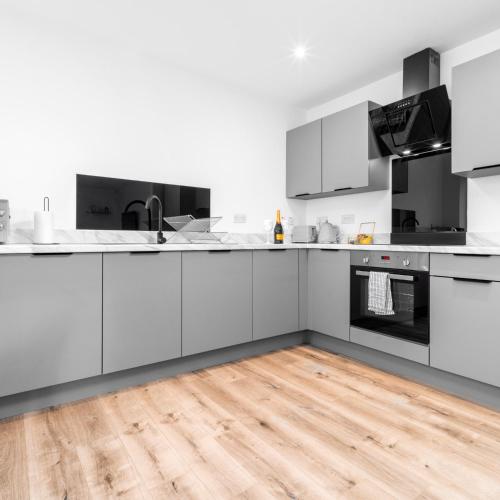a kitchen with white cabinets and a wooden floor at Stylish 2 Bed Apartment - Balcony - Private Parking - Netflix 4MC in Birmingham
