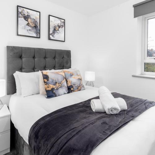a white bedroom with a large bed with a black headboard at Stylish 2 Bed Apartment - Balcony - Private Parking - Netflix 4MC in Birmingham