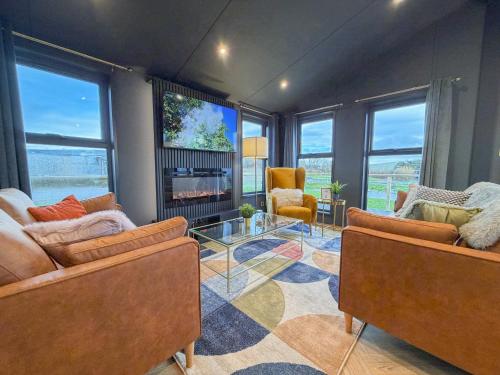 een woonkamer met twee banken en een open haard bij Blackthorn Timber Lodge in Bothel