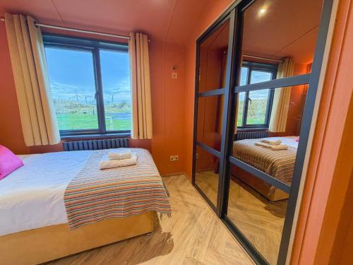 een kleine kamer met een bed en een spiegel bij Blackthorn Timber Lodge in Bothel