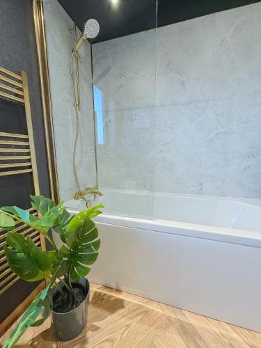 a bathroom with a white tub and a plant at Blackthorn Timber Lodge in Bothel
