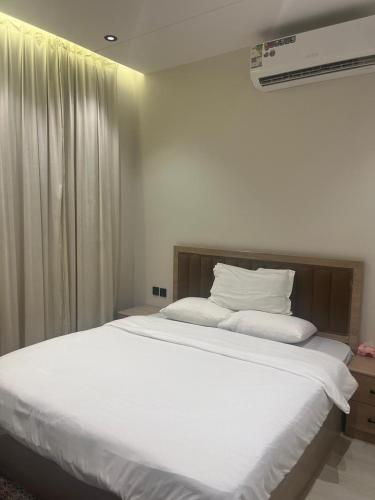 een slaapkamer met een groot bed met witte lakens bij الوسام ان in Taif