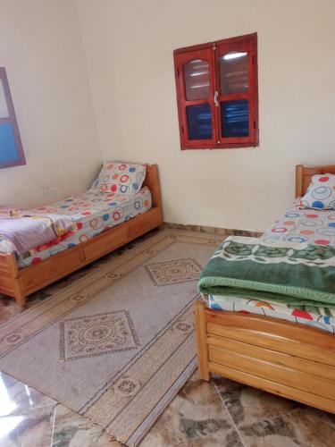 a bedroom with two beds and a window at Chezidar Tafadna Essaouira in Aït Mellal