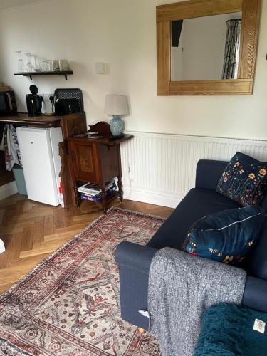 a living room with a blue couch and a rug at Tiny home in Grade 1 listed church garden in Dunham