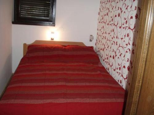 a bedroom with a red bed with a red blanket at Apartman Dragica in Poreč