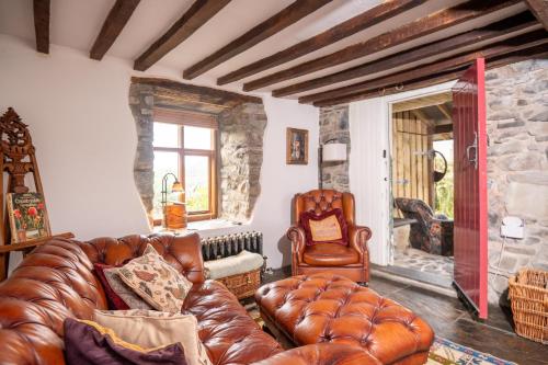 a living room with a leather couch and a chair at Panoramic Mountain Retreat - Waen Fechan - 4x4 access only in Dolgellau