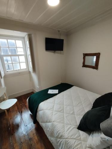 a bedroom with a large bed and a television at Pátio Da Gata in Coimbra