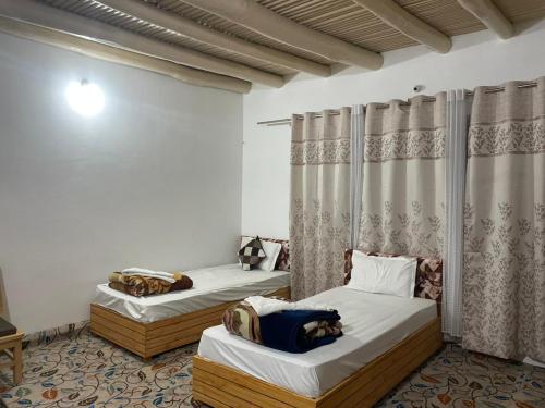 a room with two beds in a room with curtains at Baltipa Homestay in Pānāmik
