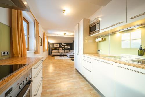 Lisl's & Gretl's Alpen Chalet - 10 Min zur Piste في سالفلدن ام ستينه مير: مطبخ مع دواليب بيضاء وغرفة معيشة