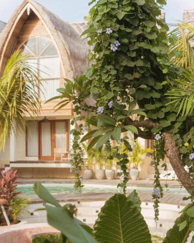 a tree with purple flowers on it in front of a house at Lulu's Wellness Boutique Villas in Uluwatu