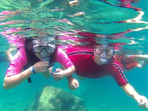 two people are swimming in the water at Club Cantamar Beach Hotel & Marina in La Paz