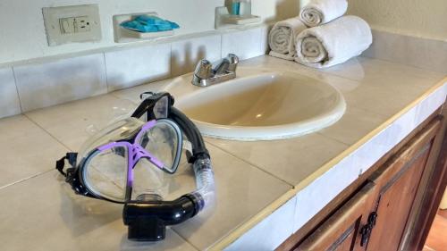 a bathroom counter with a sink and a pair of goggles at Club Cantamar Beach Hotel & Marina in La Paz
