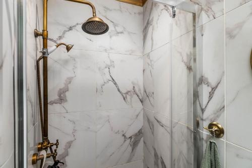 La salle de bains est pourvue d'une douche et de murs en marbre blanc. dans l'établissement Just Sezimbra- Modern Apt 3 Min from Beach, à Sesimbra