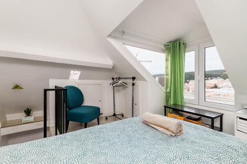 une chambre avec un lit bleu et une chaise verte dans l'établissement Just Sezimbra- Modern Apt 3 Min from Beach, à Sesimbra