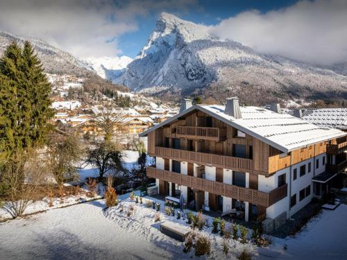 a building with a snow covered mountain in the background at Lodge Sami - OVO Network in Samoëns