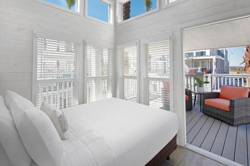 ein weißes Schlafzimmer mit Bett und Balkon in der Unterkunft Sun Outdoors San Diego Bay in Chula Vista
