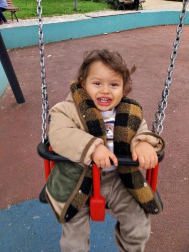 un niño está sentado en un columpio en Capital, en Almada