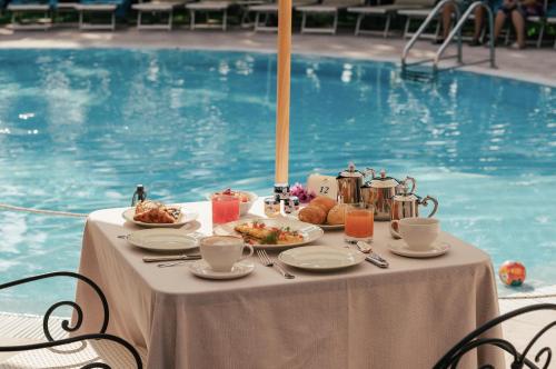ガルドーネ・リヴィエラにあるHotel Savoy Palaceのプールサイドのテーブル