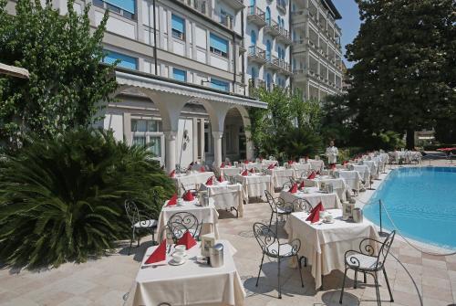 ガルドーネ・リヴィエラにあるHotel Savoy Palaceのプール横のテーブルと椅子