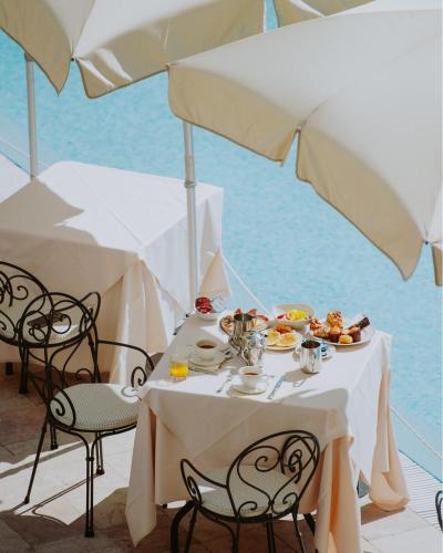 ガルドーネ・リヴィエラにあるHotel Savoy Palaceの食べ物の皿と傘が置かれたテーブル