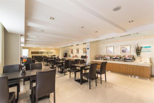 a restaurant with black tables and chairs and a counter at Jinjiang Inn - Yancheng East Huanghai Road Zhaoshang Hotel in Yancheng