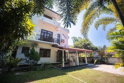 a large white house with a balcony and palm trees at Samaro Resort in Mirissa