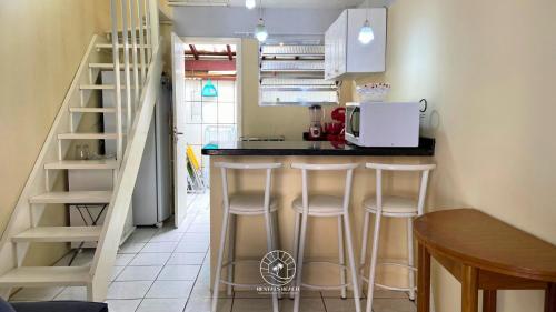 Una cocina con encimera y taburetes en una habitación. en Sobrado aconchegante próximo do mar, en Passo de Torres