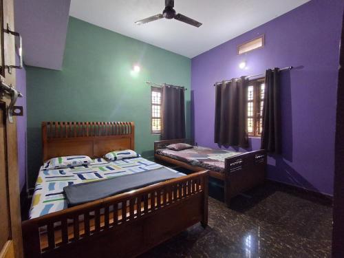 two beds in a room with purple and green walls at Homestay Nandana Full apartment with Kitchenware in Gokarna