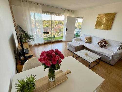 un salon avec un vase de fleurs sur une table dans l'établissement Appartement vue sur Tour Eiffel, à Garches