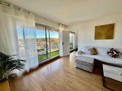 un salon avec un canapé et une grande fenêtre dans l'établissement Appartement vue sur Tour Eiffel, à Garches